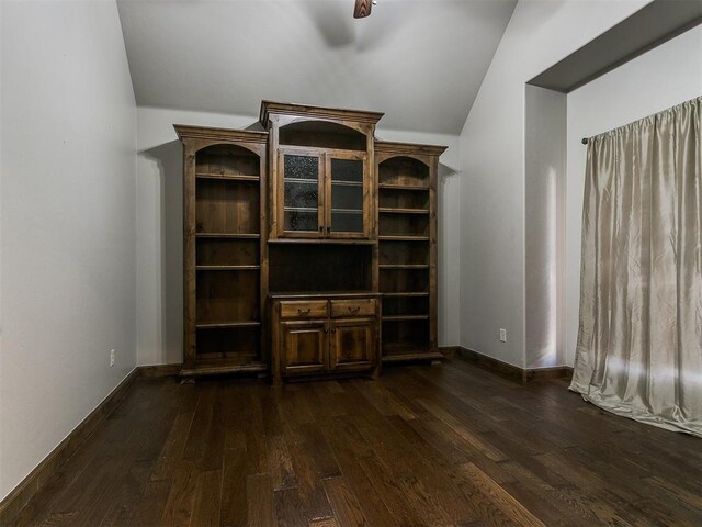 unfurnished living room featuring dark wood-type flooring, vaulted ceiling, baseboards, and a ceiling fan