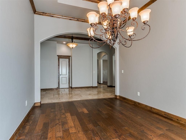 unfurnished room with baseboards, arched walkways, ornamental molding, hardwood / wood-style floors, and a chandelier