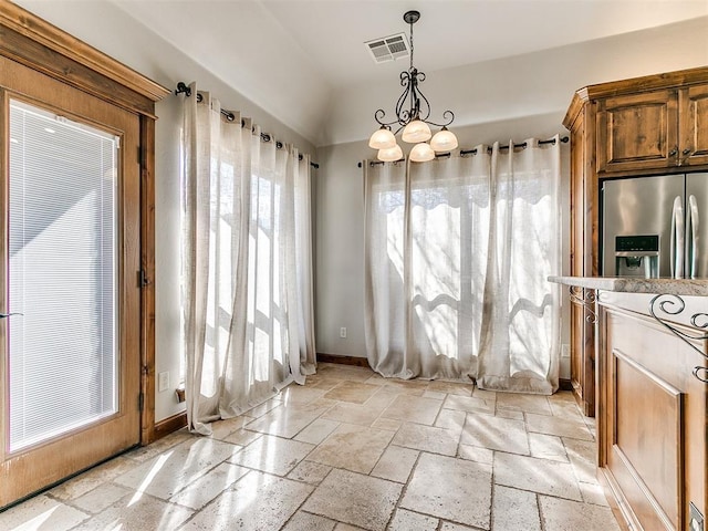 interior space featuring stone tile flooring, visible vents, vaulted ceiling, a chandelier, and baseboards