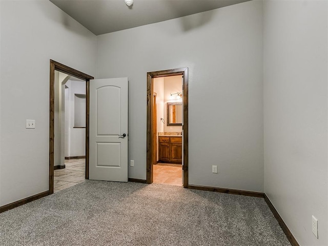 unfurnished bedroom with light colored carpet, connected bathroom, and baseboards