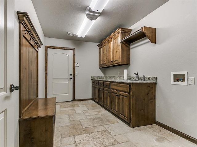 laundry area with hookup for a washing machine, a sink, visible vents, cabinet space, and stone tile flooring