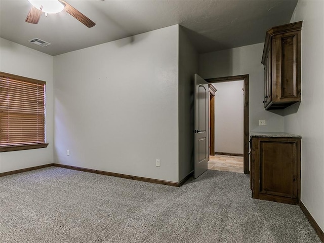 unfurnished room featuring ceiling fan, baseboards, visible vents, and light colored carpet