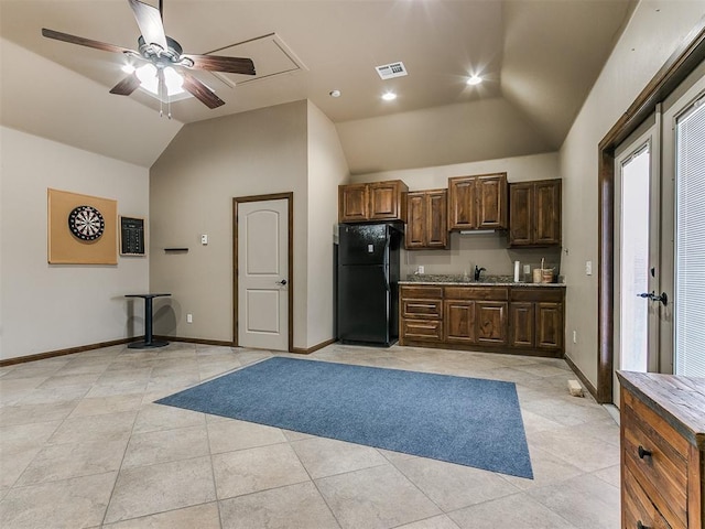 kitchen featuring light tile patterned floors, lofted ceiling, freestanding refrigerator, a sink, and baseboards