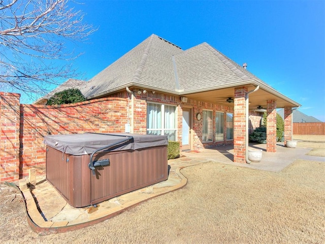 rear view of property with a ceiling fan, roof with shingles, fence, a patio area, and brick siding