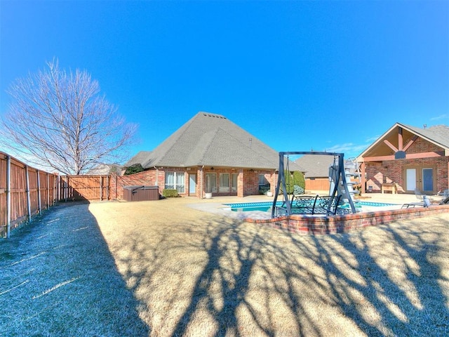 rear view of property featuring a fenced in pool, brick siding, a gate, a patio area, and fence