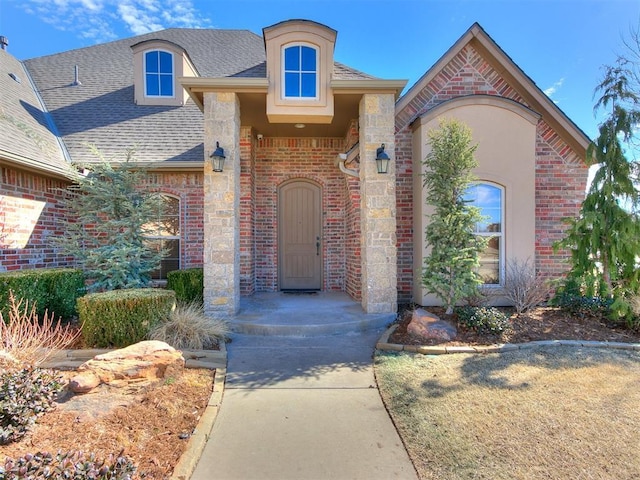 property entrance featuring roof with shingles and brick siding