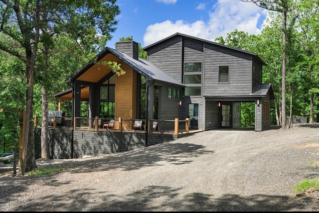 view of front of house featuring metal roof, driveway, and a chimney