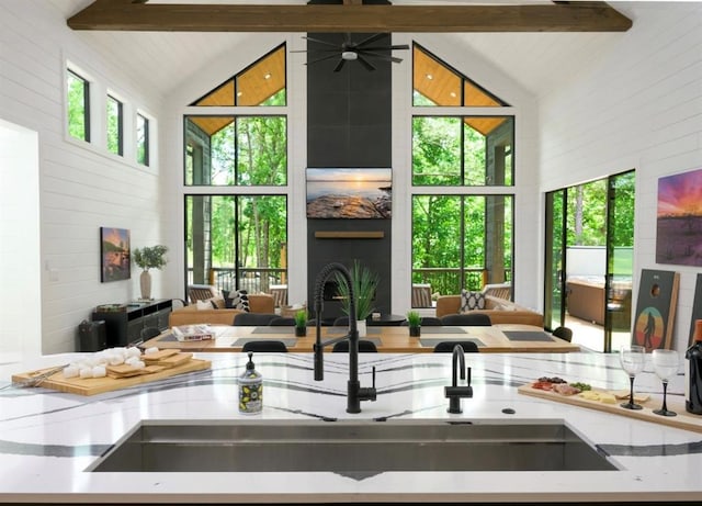 interior space featuring a large fireplace, a sink, lofted ceiling with beams, and ceiling fan