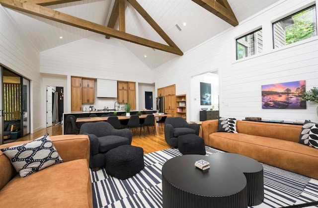 living room with high vaulted ceiling, light wood-type flooring, and beamed ceiling