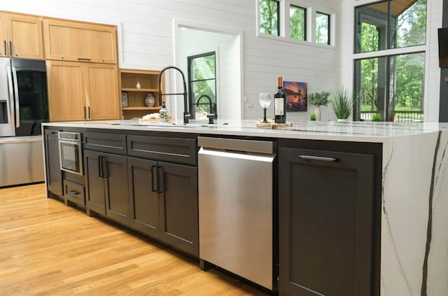 kitchen featuring plenty of natural light, appliances with stainless steel finishes, light countertops, light wood-style floors, and a sink