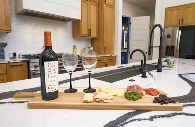 kitchen featuring brown cabinets, light countertops, custom range hood, decorative backsplash, and appliances with stainless steel finishes