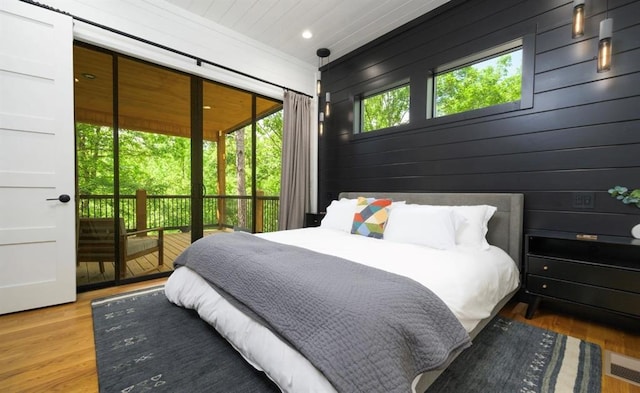 bedroom with recessed lighting, wood walls, wood finished floors, visible vents, and access to outside