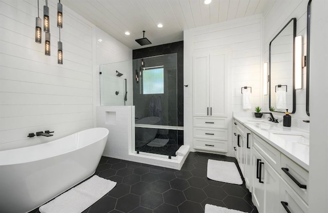 full bath with a freestanding tub, a sink, tile patterned floors, double vanity, and a stall shower