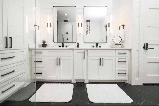 full bathroom with a sink, double vanity, a stall shower, and tile patterned flooring