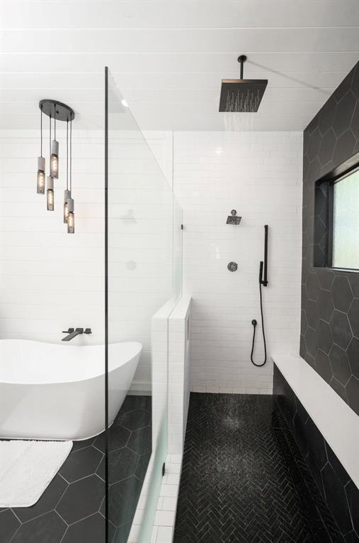 bathroom featuring tile patterned flooring, a soaking tub, a tile shower, and tile walls