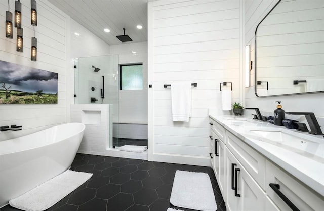 bathroom with double vanity, a tile shower, a sink, and tile patterned floors