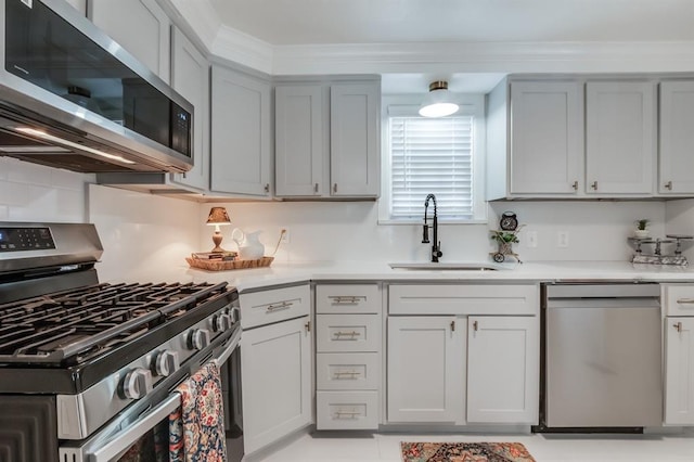 kitchen with ornamental molding, stainless steel appliances, a sink, and light countertops