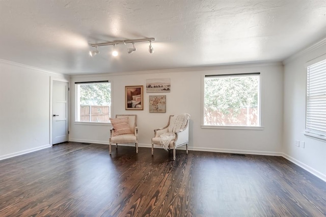 living area with baseboards, dark wood finished floors, track lighting, and ornamental molding