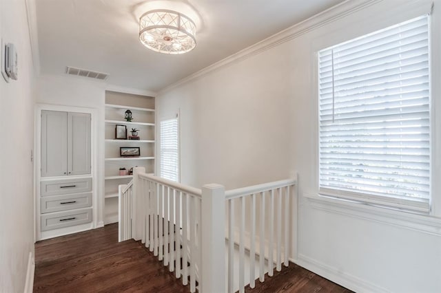 interior space featuring built in features, crown molding, visible vents, and wood finished floors