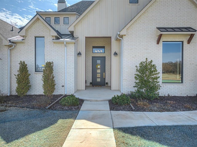 view of exterior entry with board and batten siding and a chimney