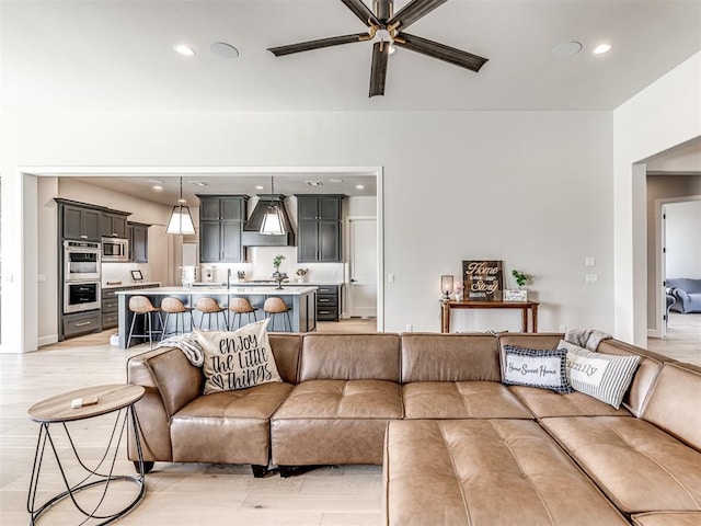 living area with light wood finished floors, a ceiling fan, and recessed lighting