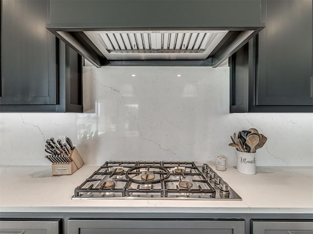 kitchen featuring stainless steel gas cooktop, light countertops, ventilation hood, and gray cabinetry