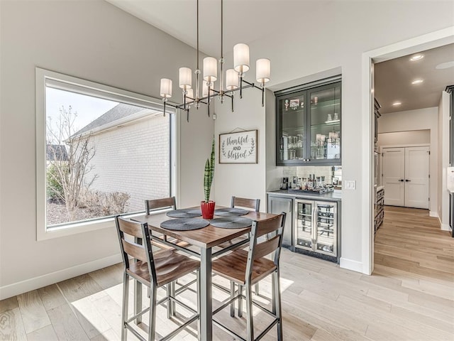 dining space with light wood-type flooring, baseboards, plenty of natural light, and a dry bar