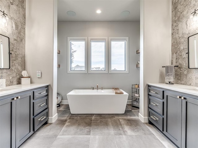 bathroom featuring a freestanding bath, two vanities, toilet, and recessed lighting