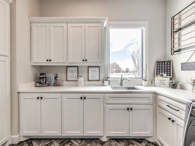 kitchen with range, light countertops, white cabinets, and a sink