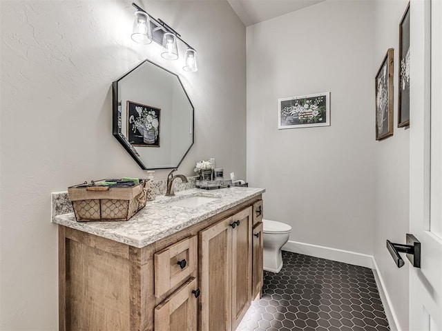 half bath featuring tile patterned floors, vanity, toilet, and baseboards