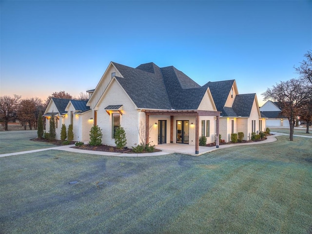 view of front facade with metal roof, brick siding, a standing seam roof, and a front lawn