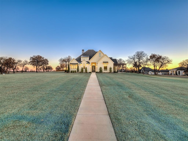 french country home featuring a yard, a chimney, and board and batten siding