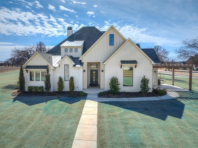 view of front of house with a chimney, a standing seam roof, and a front yard