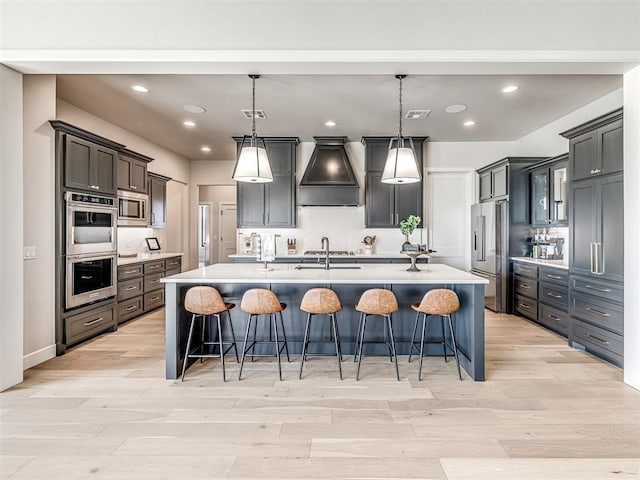 4716 Moulin Rd, Edmond, OK 73034 - kitchen with light countertops, appliances with stainless steel finishes, custom exhaust hood, and light wood finished floors