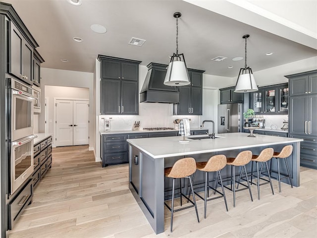 4716 Moulin Rd, Edmond, OK 73034 - kitchen featuring a sink, light wood-style floors, stainless steel appliances, visible vents, and custom exhaust hood