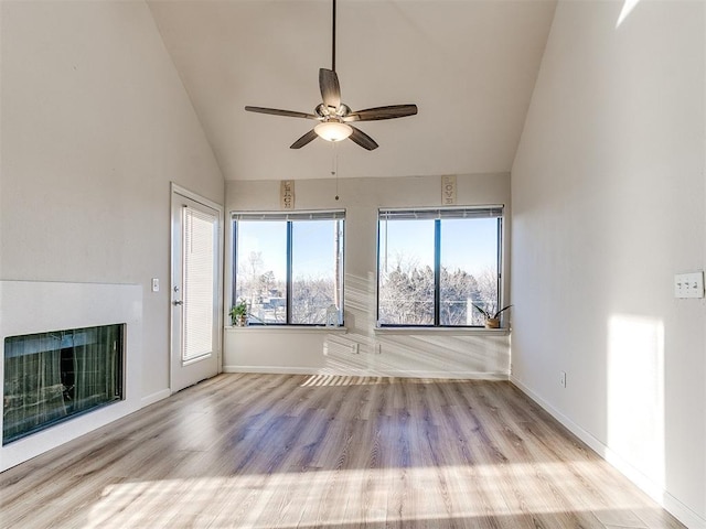 unfurnished living room featuring ceiling fan, a fireplace, wood finished floors, and baseboards