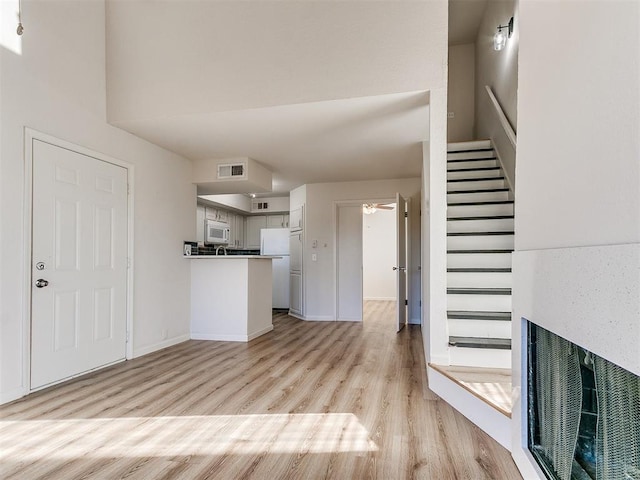 kitchen with visible vents, a ceiling fan, light wood-type flooring, white appliances, and a peninsula