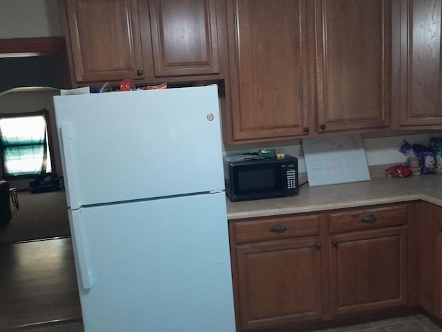 kitchen featuring black microwave, light countertops, and freestanding refrigerator