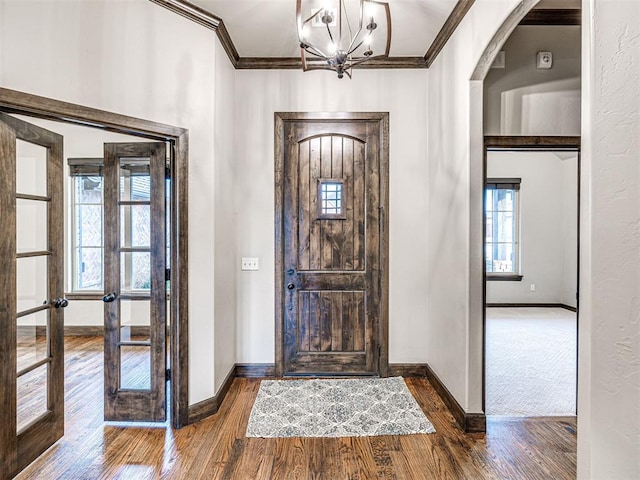 entryway with baseboards, arched walkways, dark wood finished floors, and crown molding