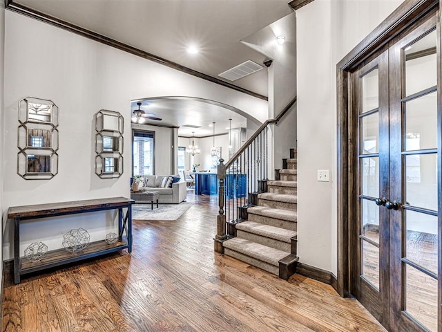 entryway featuring visible vents, arched walkways, wood finished floors, stairs, and crown molding