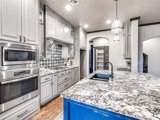 kitchen with arched walkways, a barn door, a sink, visible vents, and appliances with stainless steel finishes