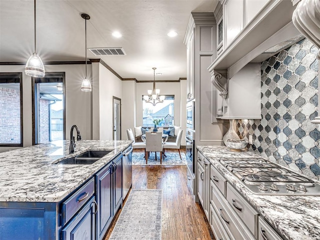 kitchen with tasteful backsplash, visible vents, ornamental molding, blue cabinets, and a sink