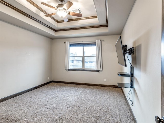 carpeted empty room featuring ornamental molding, a tray ceiling, visible vents, and baseboards