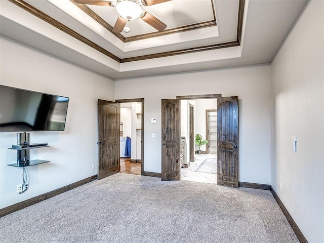 unfurnished bedroom featuring carpet, crown molding, a tray ceiling, and baseboards