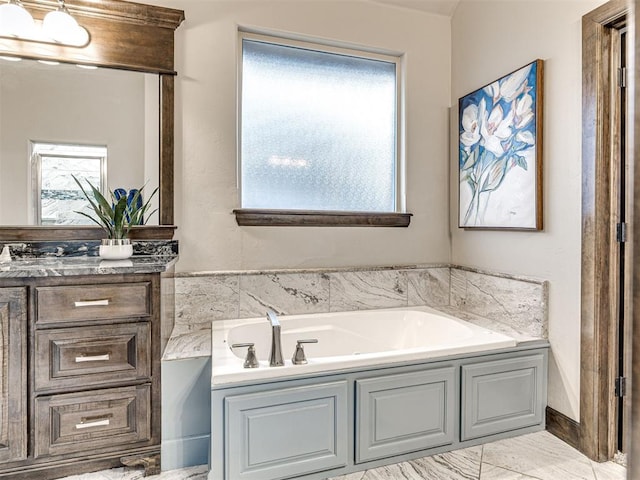 bathroom with marble finish floor, a garden tub, and vanity