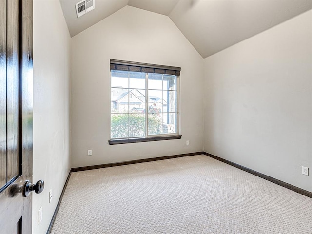 spare room with carpet floors, lofted ceiling, visible vents, and baseboards