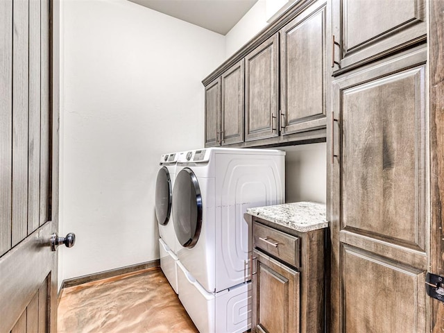 clothes washing area featuring cabinet space, baseboards, and washer and dryer