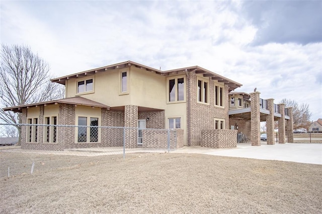 rear view of property with stucco siding, fence, and brick siding