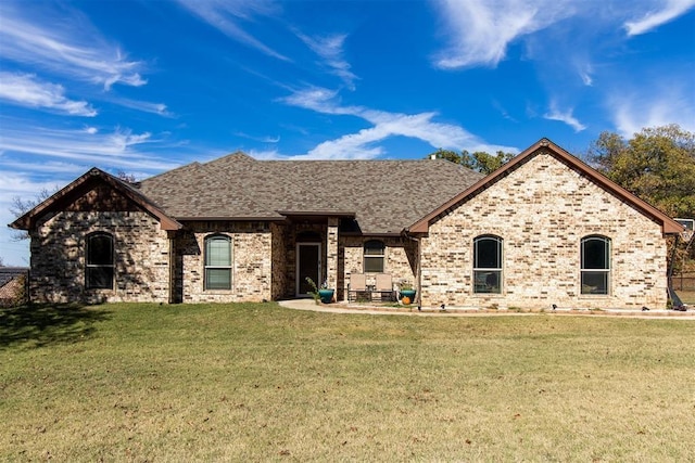 view of front facade featuring a front yard, brick siding, and roof with shingles