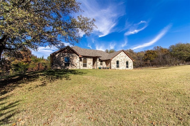 view of front of house with stone siding, a front lawn, and fence